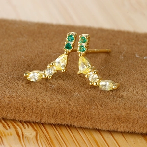 Macro shot of gold fruit stud earrings with emerald green and yellow zircon stones