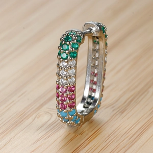 Primo piano di orecchini huggie rettangolari con pietre pavé colorate verde, bianco, rosso e blu