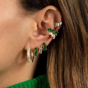 Dettaglio di ear cuff placcati oro 18k con zirconi verdi indossati da una modella