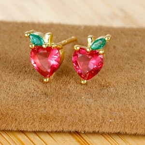 Macro view of heart shaped red zircon fruit earrings with 18K gold plated leaves
