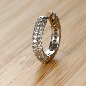 Dettaglio macro di zirconi a pavé su un orecchino a cerchio in argento con cerniera