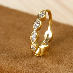 Detail van gouden huggie-oorbel met marquise geslepen zirkonia op bruin fluweel