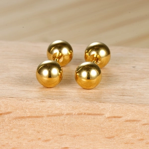 Vue macro de boucles d'oreilles boules dorées à double extrémité sur support bois