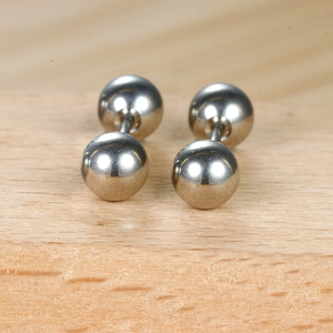 Macro de boucles d'oreilles boules en argent poli sur une surface en bois naturel