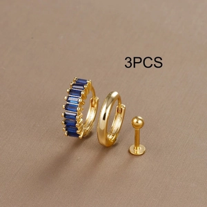 Detailed shot of 3-piece gold earring set with blue zircon inlay on textured surface