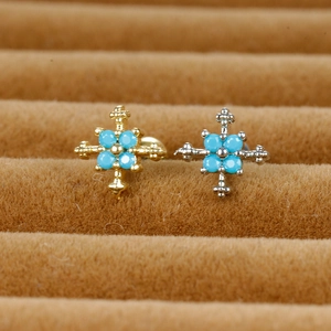 Detailed view of vintage cross stud earrings with turquoise stones in gold and silver