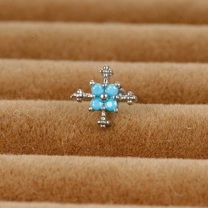 Macro view of silver cross stud earring with blue turquoise beads on a display tray