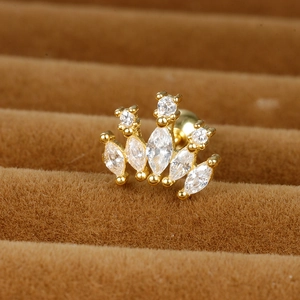 Macro shot of gold crown cartilage stud with sparkling cubic zirconia on brown velvet