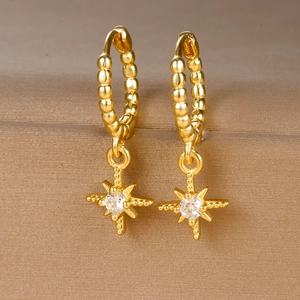 Detailopname van 18k gouden ster oorbellen met zirkoonsteentjes en kralen textuur design