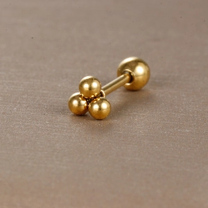 Détail du piercing cartilage en acier doré à trois billes avec fermeture à vis sécurisée