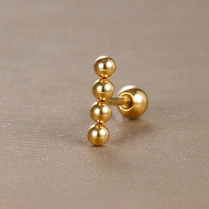 Vue macro de boucles d'oreilles en acier inoxydable doré à quatre billes et vis