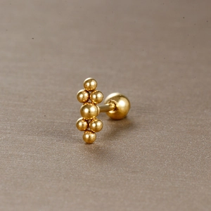 Détail macro de clous d'oreilles boules dorés géométriques avec fermeture à vis sur fond texturé