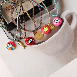 Detail of colorful woven bracelets with evil eye, lucky square charms, and fish pendants