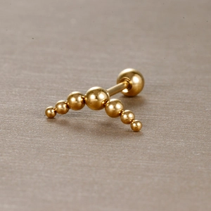Vue macro d'un piercing en acier inoxydable doré avec perles de taille dégradée