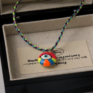 Macro detail of hand-woven colorful fiber cord with evil eye enamel pendant charm