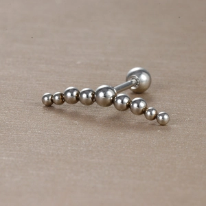 Gros plan sur un piercing en acier inoxydable argenté avec perles en métal poli dégradé