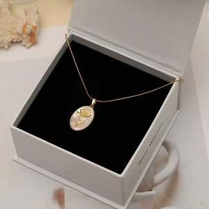 Gros plan du collier ovale doré avec incrustation en nacre et relief floral en boîte