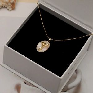 Gros plan du pendentif floral en or avec incrustation de nacre dans un écrin blanc élégant