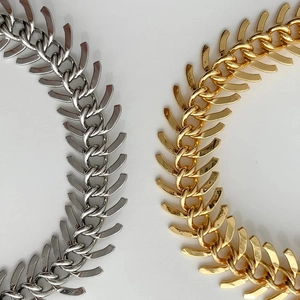 Detailed close-up of gold and silver fishbone chain necklaces with polished 18K finish