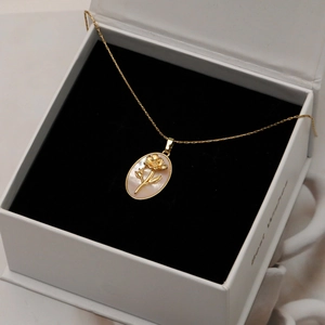 Collier doré avec pendentif ovale en nacre et motif floral dans une boîte cadeau chic