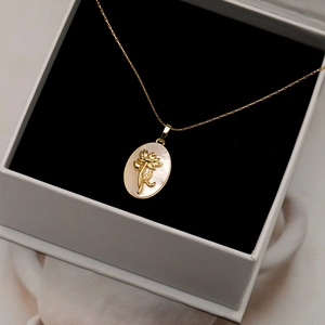 Collier avec pendentif ovale doré incrusté de nacre et motif floral en relief