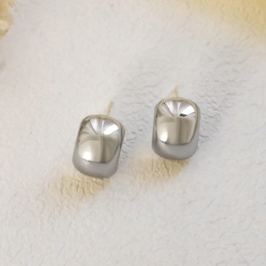Macro shot of minimalist silver bean earrings with a polished mirror finish surface