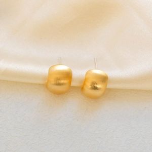 Detailed close-up showing the matte brushed texture of golden round stud earrings