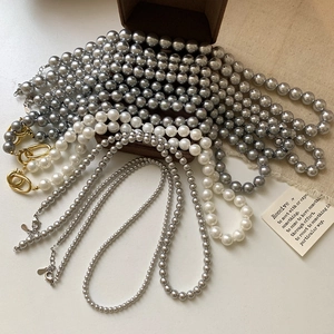 Collier de perles gris argenté et blanc avec fermoir doré sur écrin en velours
