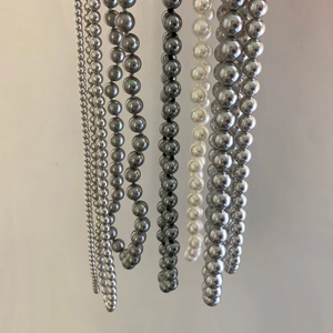 Détail montrant diverses tailles et nuances de colliers de perles rondes grises