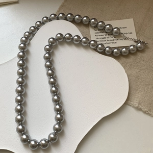 Détail de collier en perles gris argenté avec fermoir mousqueton et éclat métallique poli