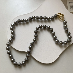 Vue détaillée du collier de perles gris argenté doté d'un fermoir métallique doré noué