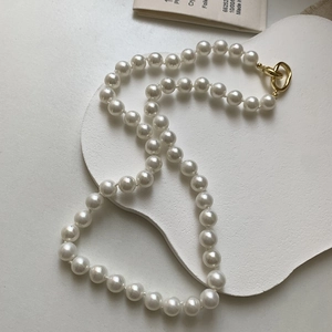 Gros plan détaillé d'un collier de perles grises rondes avec un fermoir OT doré