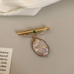 Detail of baroque purple pearl brooch with green agate stone and golden metal bar