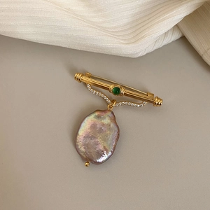Detail of baroque purple pearl brooch with green gemstone and zircons in gold setting