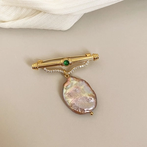 Vintage gold brooch featuring a green gemstone and a large baroque freshwater pearl pendant