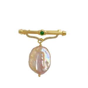 Baroque lavender pearl brooch with green gemstone and gold plating on white background