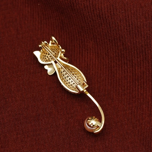 Vue arrière d'une broche chat dorée avec texture maillée et détail d'une perle rose