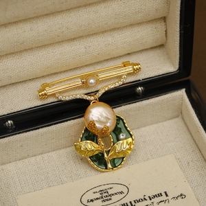 Vintage gold brooch with baroque pearl and green enamel leaf in a jewelry box
