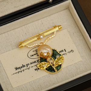Vintage gold brooch featuring a large baroque pearl and green enamel leaf detail