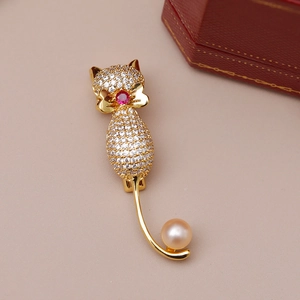 Détail d'une broche chat plaqué or avec zircons blancs et une perle rose élégante