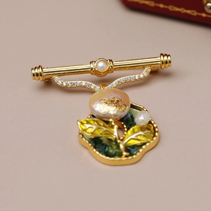 Detailed close-up of a flower brooch with baroque pearl, gold leaf, and green enamel