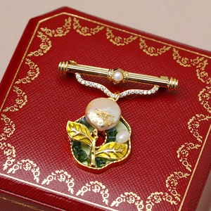Macro detail of French vintage brooch with baroque pearl and green enamel leaf on red box
