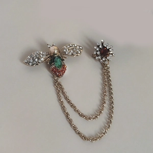 Detail of vintage honey bee brooch with green emerald and rhinestone chain accents