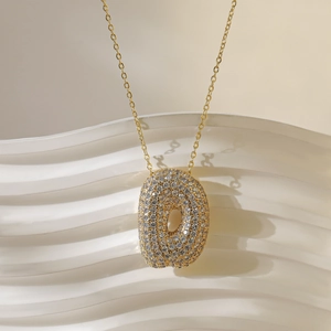 Detail van de gouden ovale letter hanger met witte zirkoon op een fijne gouden ketting