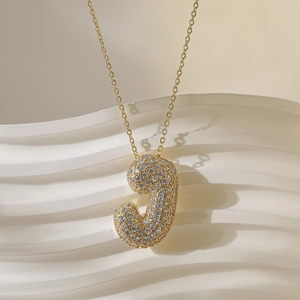 Macro-opname van gouden letter J-hanger met micro-pave gezette zirkonia kristallen