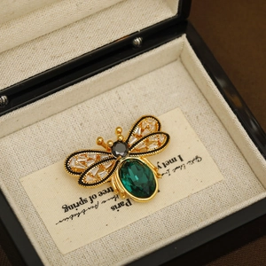 Elegant gold bee brooch with emerald crystal and white diamonds in black jewelry box