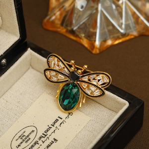 Exquisite gold-plated honey bee brooch featuring a large green emerald gemstone with crystals