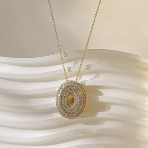 Detailopname van een gouden ovale hangerketting ingelegd met witte zirkonia steentjes