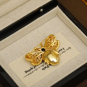 Elegant gold bee brooch with emerald accents and hollow wings in a luxury gift box