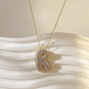 Detailweergave van de gouden ketting met letter R-hanger in ballonstijl en kristallen